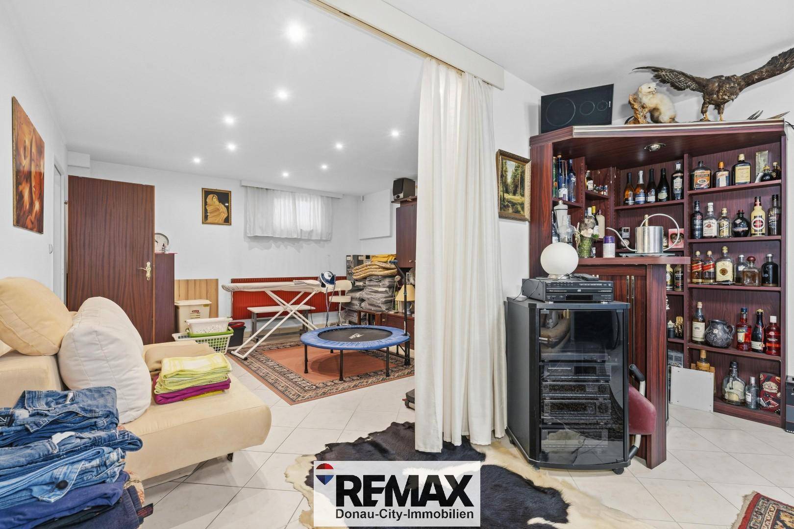 Geräumiger Kellerraum mit Hausbar, Sofa und Platz für Freizeitaktivitäten.