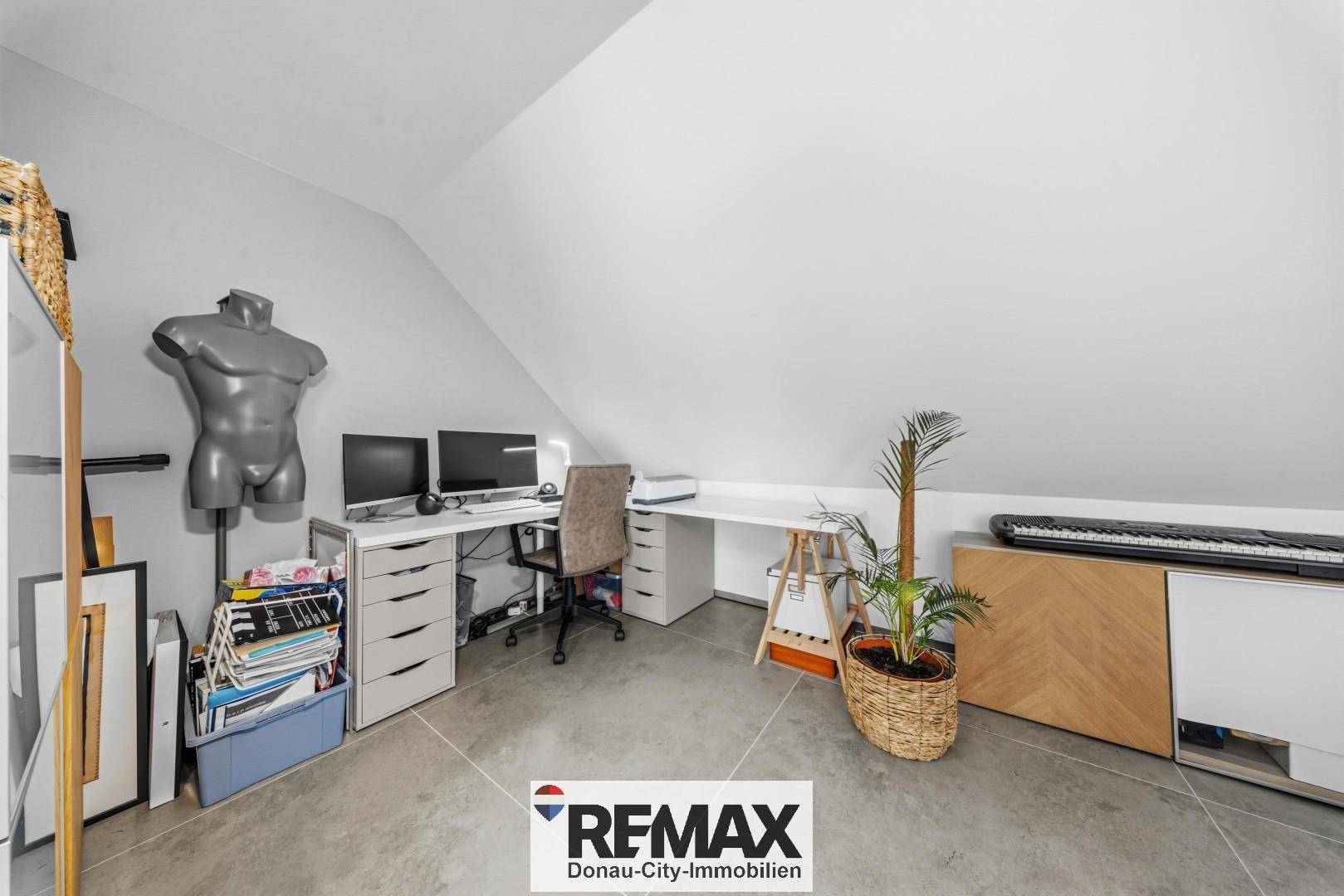 Helles Dachgeschosszimmer mit Schreibtisch, Computern und Stauraum, ideal als Büro oder Hobbyraum.