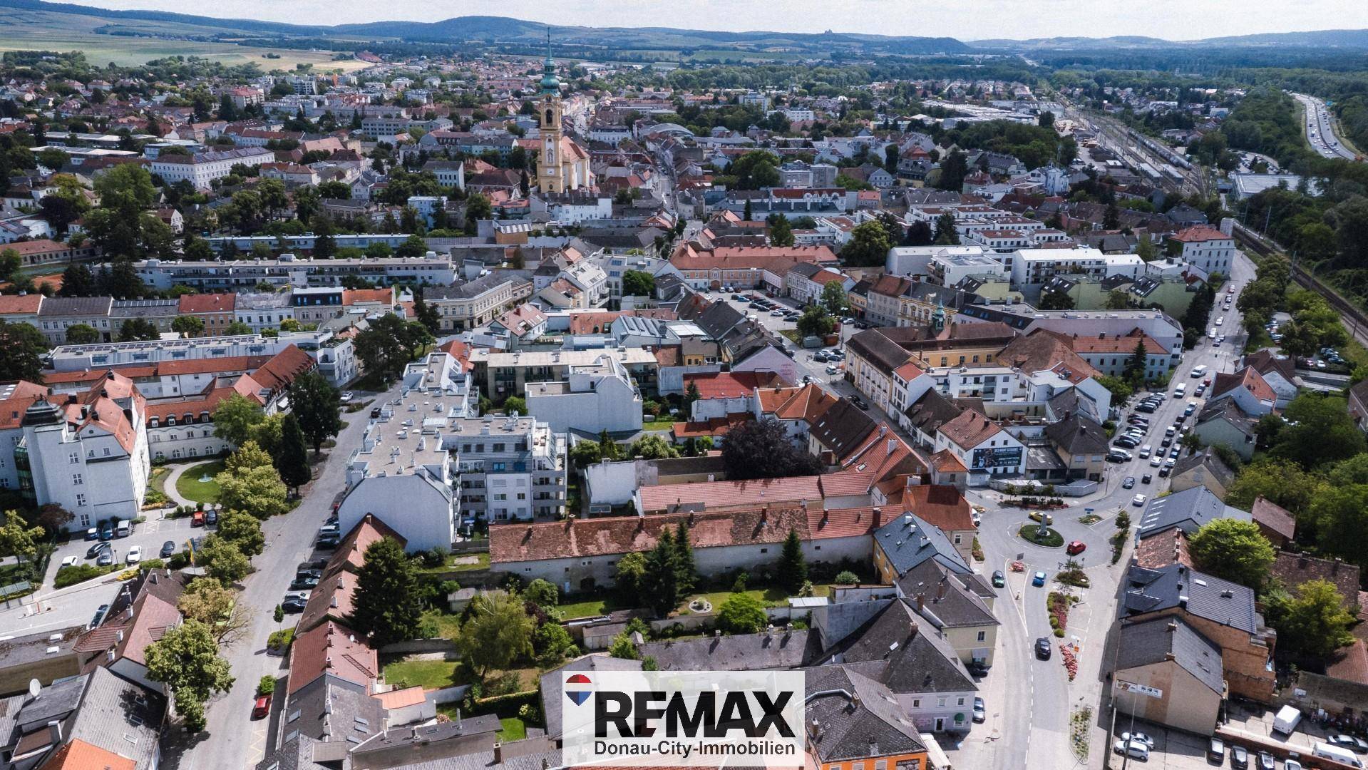 Weitläufige Luftaufnahme der Stadt mit historischer Architektur, grüner Umgebung und Fernblick.