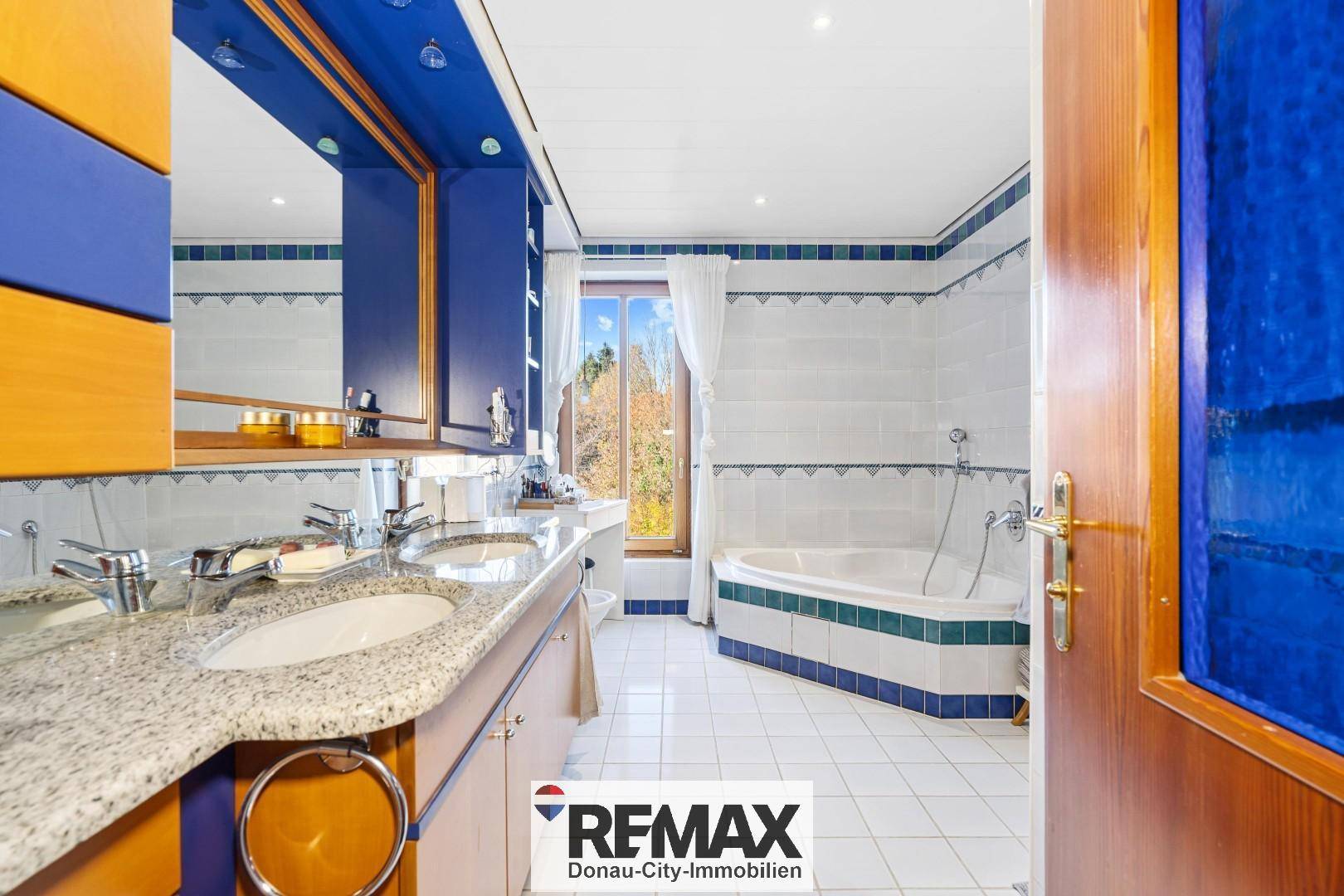 Geräumiges Badezimmer mit Doppelwaschbecken, Eckbadewanne und Fenster.