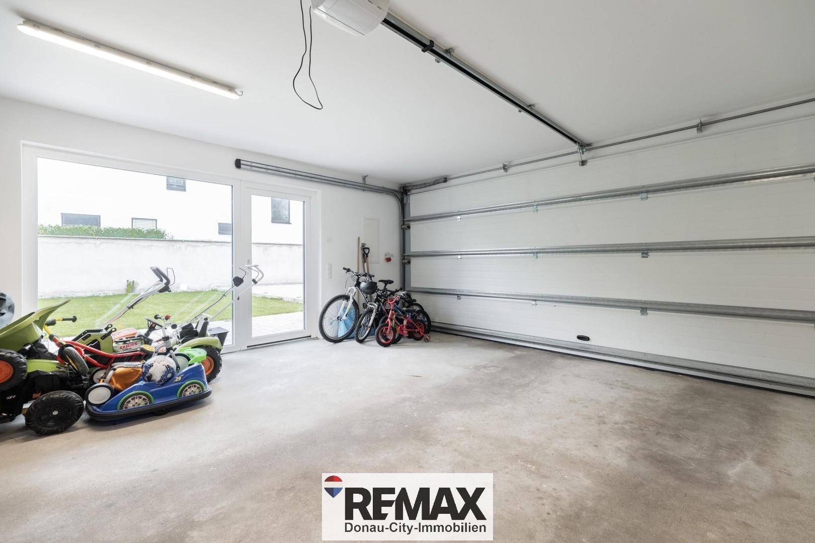 Geräumige Garage mit Rolltor, viel Platz und Zugang zum Gartenbereich.