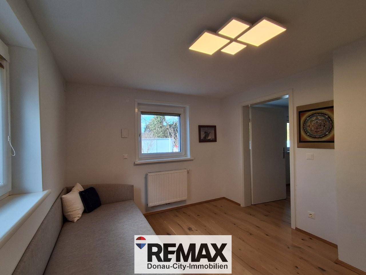 Helles Zimmer mit Tagesbett, Schreibtisch und Holzfußboden, ideal als Büro oder Gästezimmer.