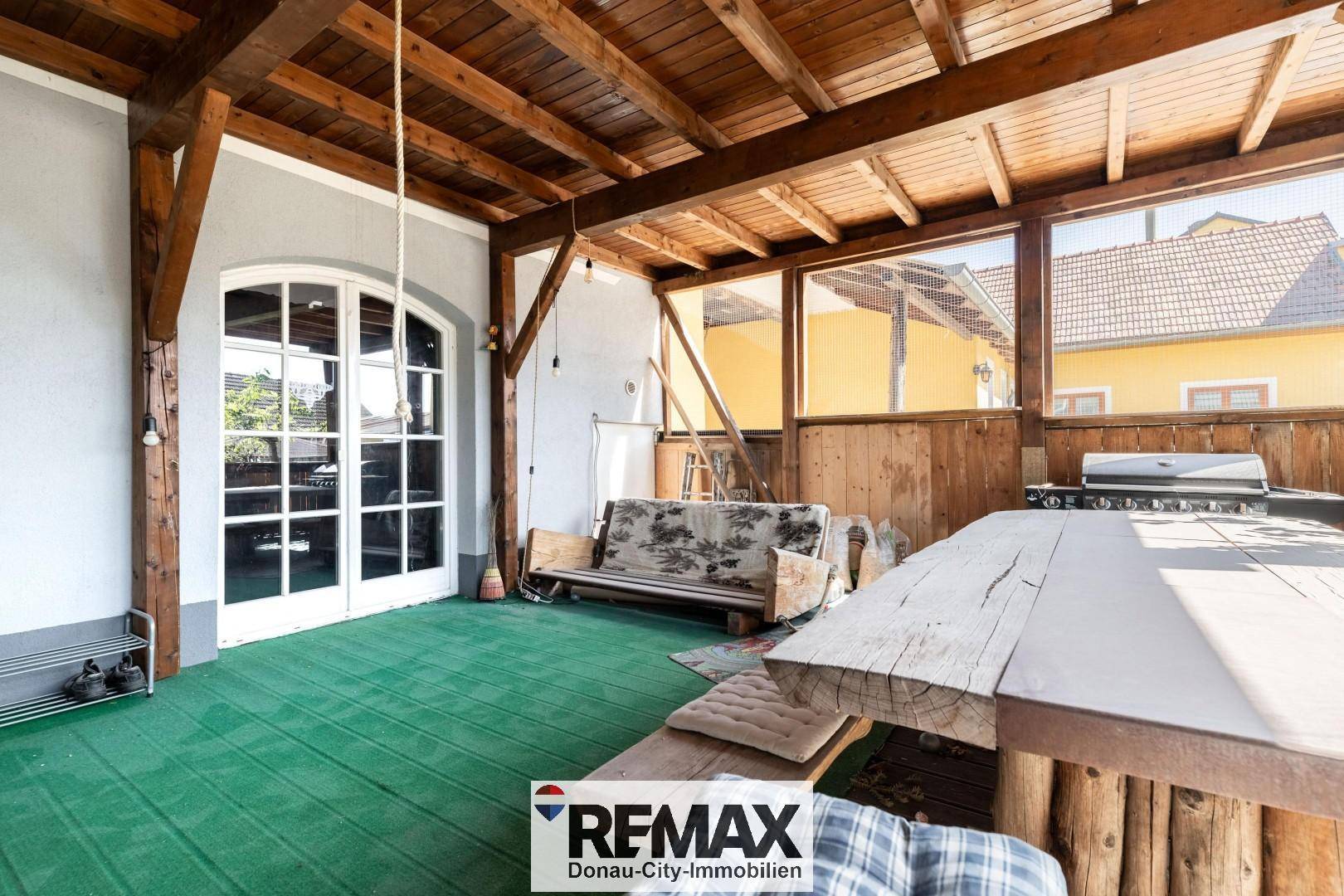 Überdachte Terrasse mit Holzbalken, Sitzgelegenheiten und Grillbereich, ideal für gesellige Stunden im Freien.