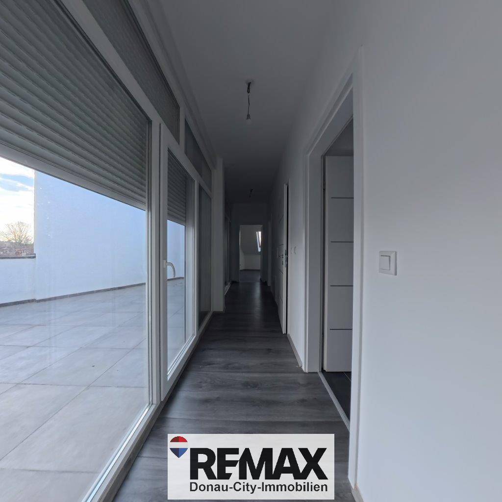 Langer, heller Flur mit Zugang zu einer Terrasse und modernem Laminatboden.