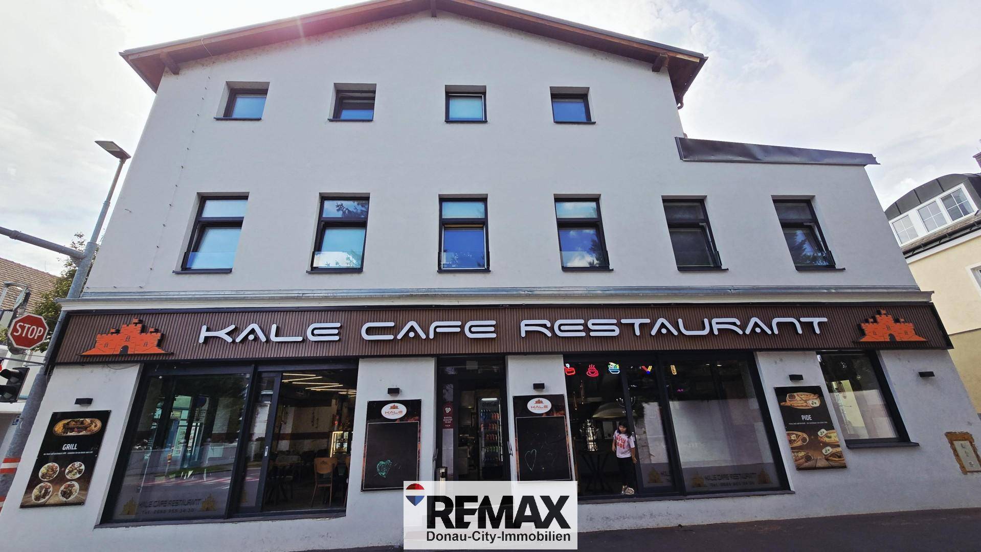 Fassade eines Geschäftsgebäudes mit Restaurant im Erdgeschoss und großen Schaufenstern.