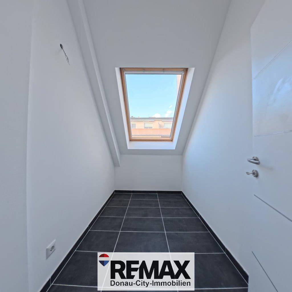 Kleiner Raum mit Dachfenster und dunklen Fliesen, ideal als Abstellraum oder Gäste-WC.