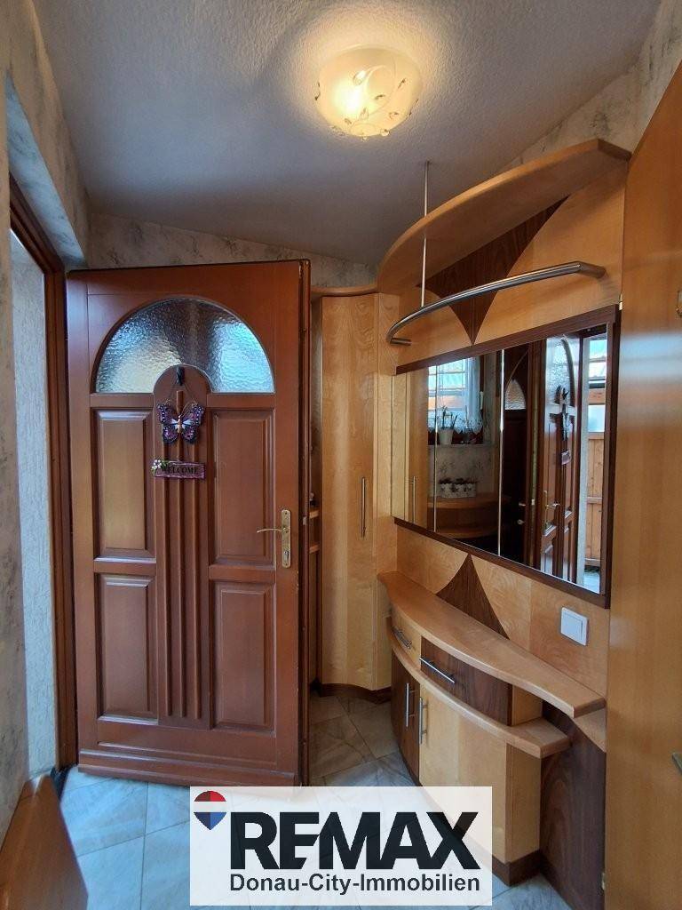 Heller Flur mit Holztür, Spiegel und praktischen Einbaumöbeln, die viel Stauraum bieten.