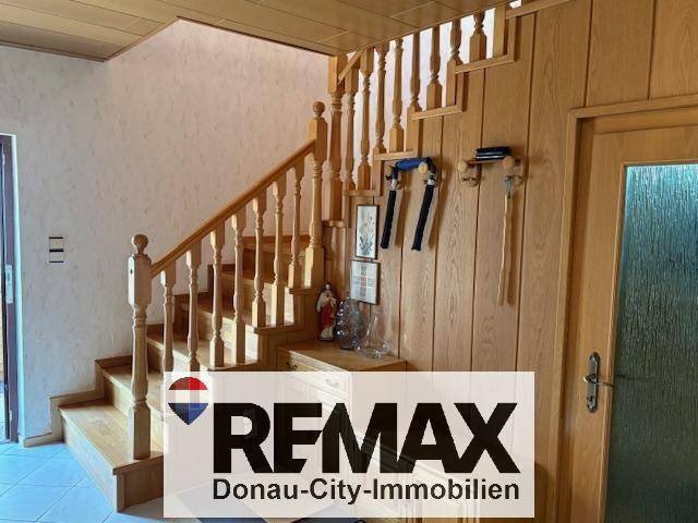 Holztreppe in einem Flur mit Holzvertäfelung an der Wand, die in die obere Etage führt.