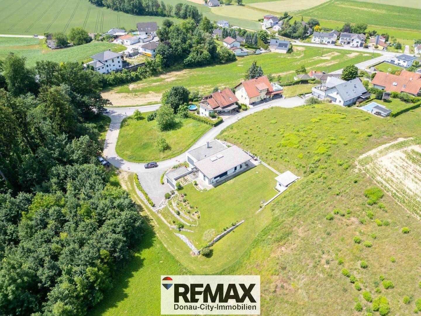 Luftaufnahme des modernen Hauses in einer weitläufigen, grünen Landschaft mit Nachbarschaft.