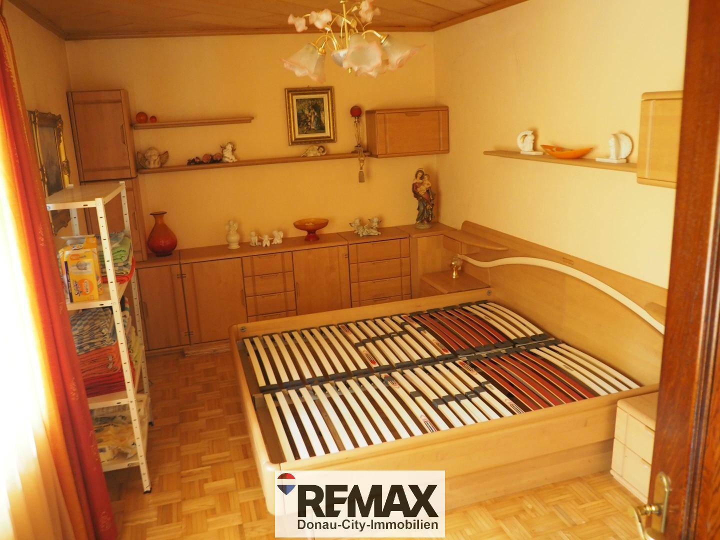 Schlafzimmer mit Holzbettrahmen, Einbauschränken und einem warmen Parkettboden.