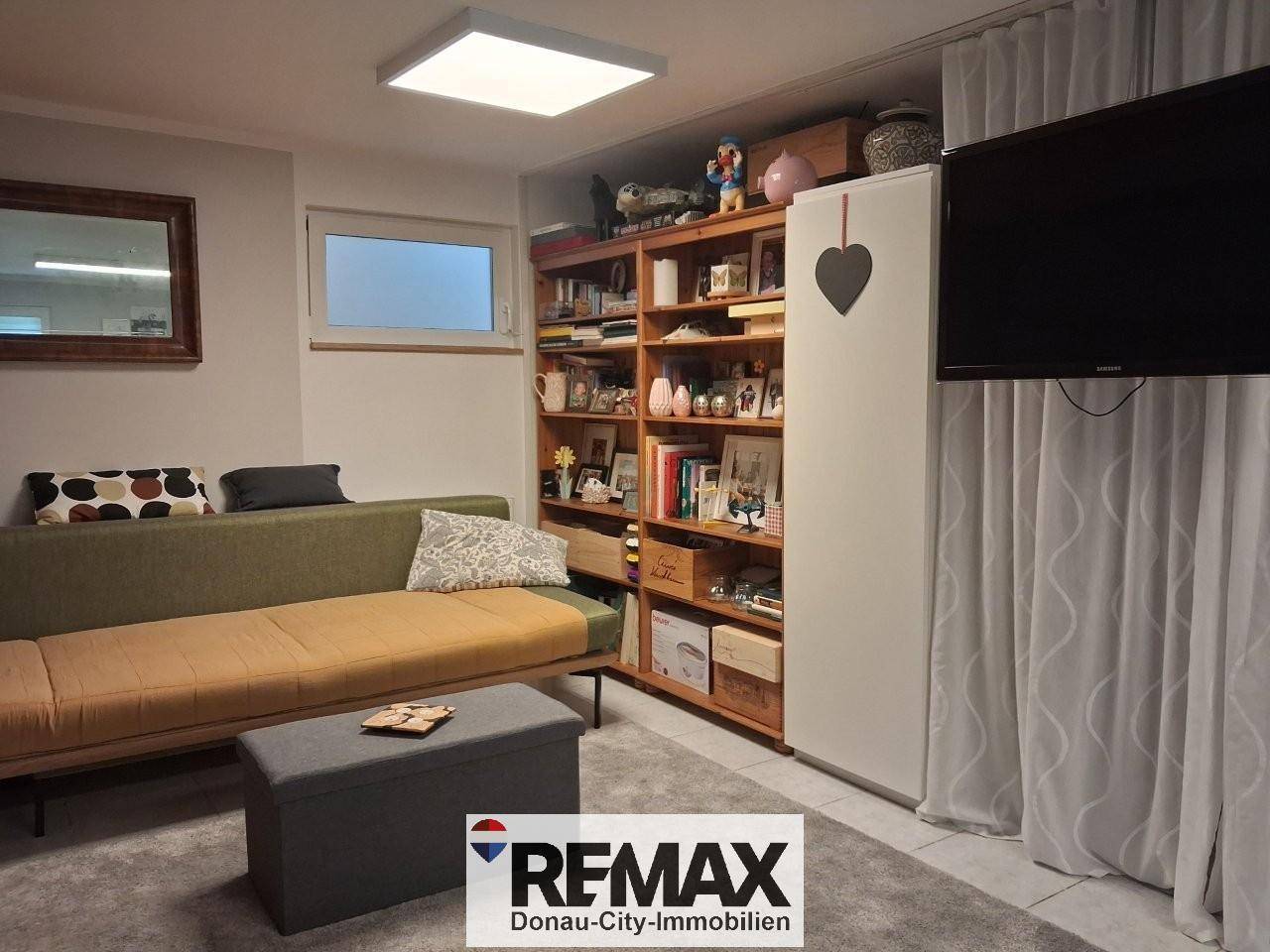 Gemütlicher Hobbyraum im Keller mit Sofa, Bücherregal und Fernseher.