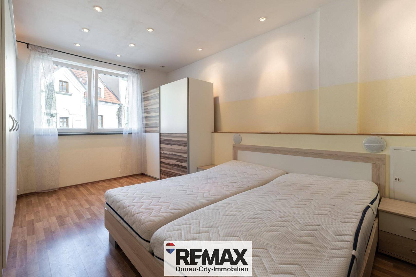Schlafzimmer mit zwei Einzelbetten, Kleiderschrank und Fenster mit Blick nach draußen.