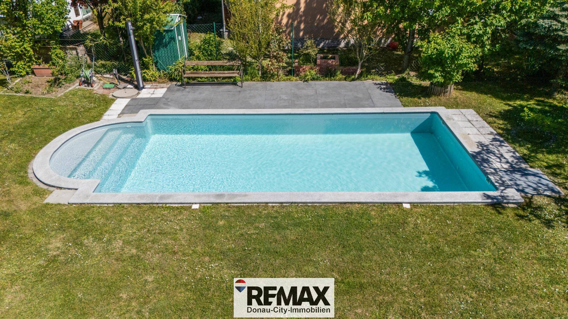Detailansicht des rechteckigen Swimmingpools mit Treppeneinstieg und umliegender Rasenfläche.