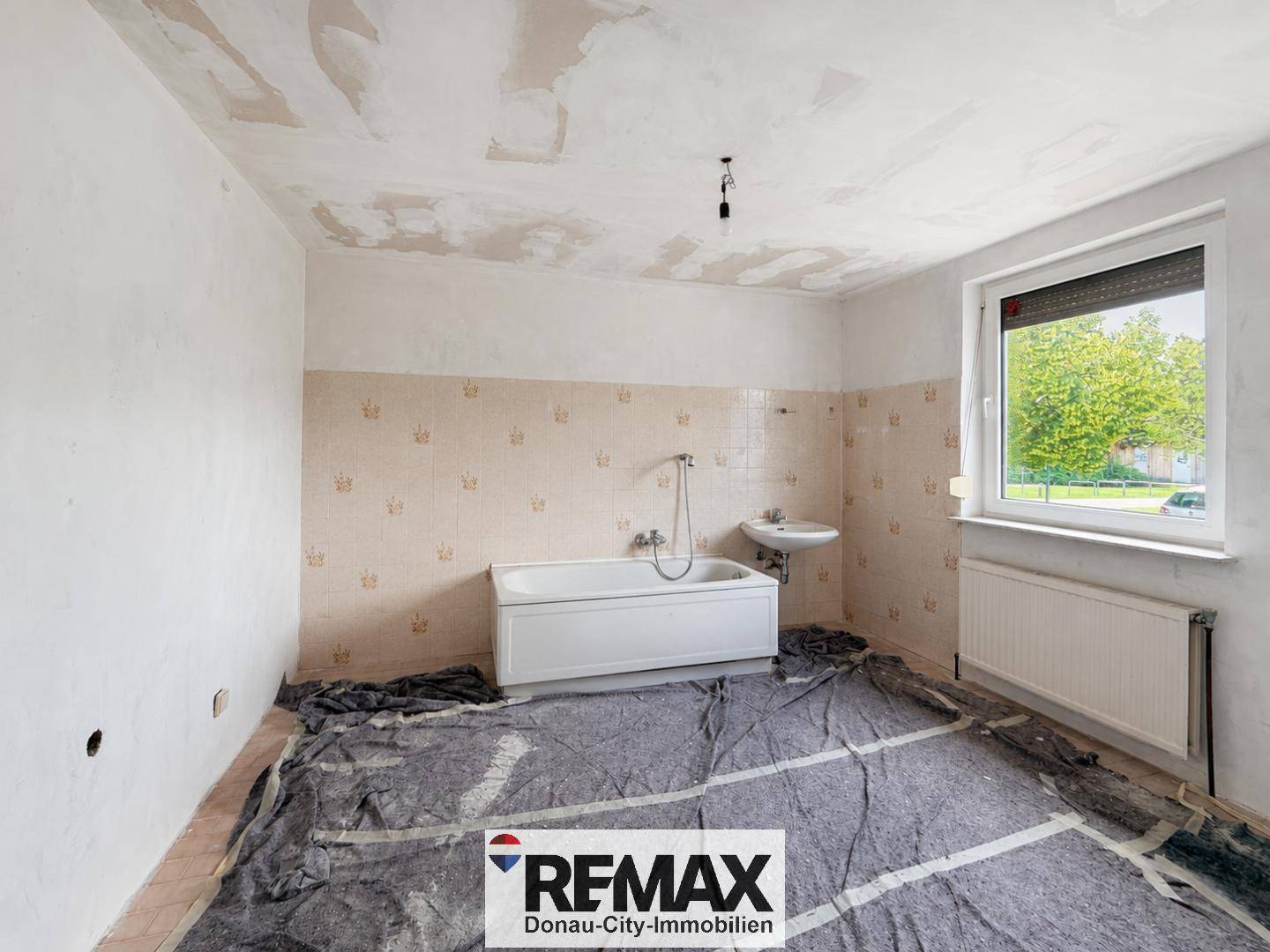 Badezimmer in Renovierung mit Badewanne, Waschbecken und Fenster.