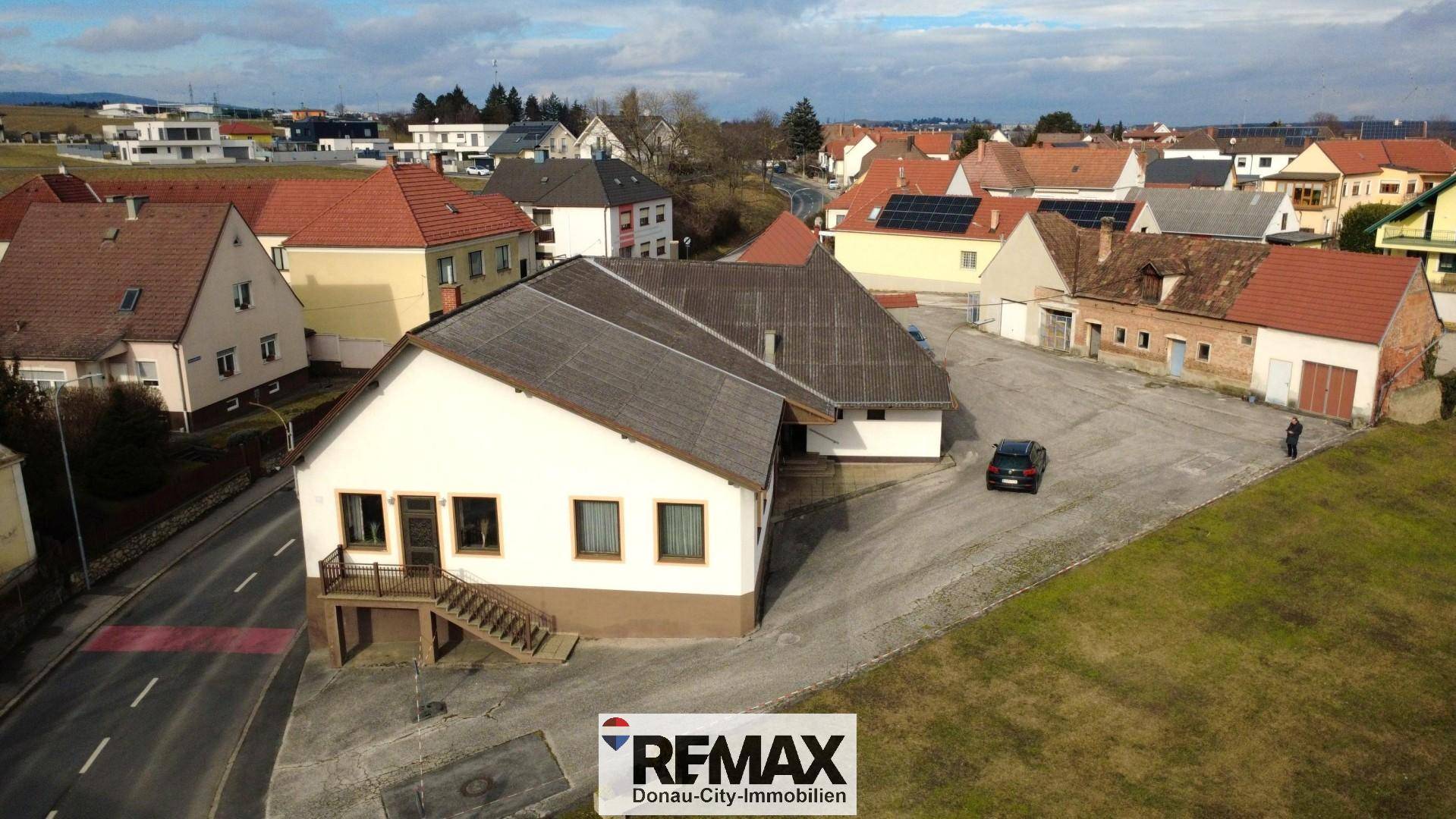 Panoramablick aus der Luft auf das Gebäudeensemble mit Zufahrt und umliegender Landschaft.