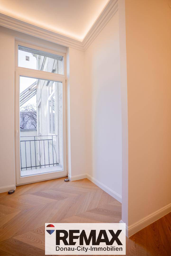 Helles Zimmer mit Fischgrätparkett und französischem Balkon, ideal für ein Schlafzimmer.