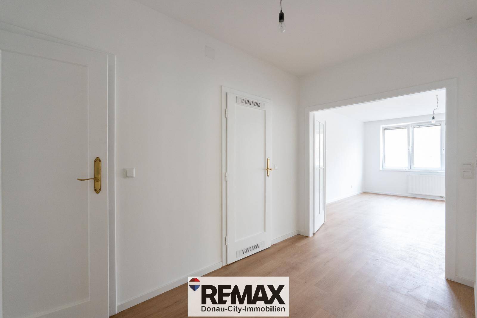 Heller Flur mit Laminatboden und weißen Türen, der zu weiteren Räumen führt.