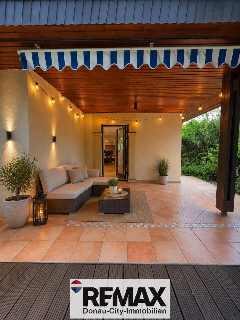 Gemütliche überdachte Terrasse mit Lounge-Möbeln und stimmungsvoller Beleuchtung.