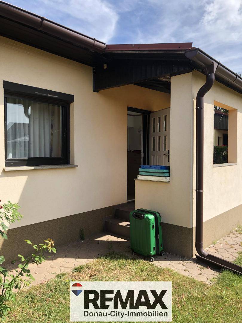 Eingangsbereich des Hauses mit einer grünen Reisetasche vor der Tür.