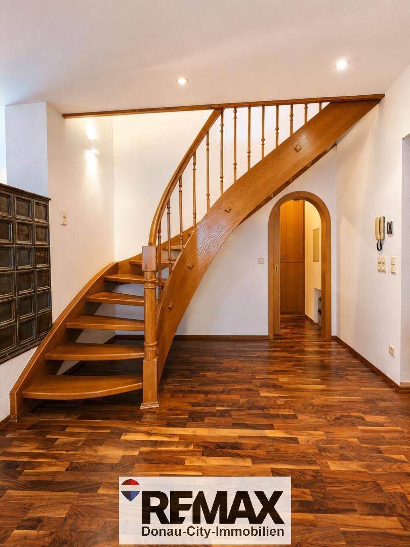 Eleganter Eingangsbereich mit geschwungener Holztreppe und Holzboden.