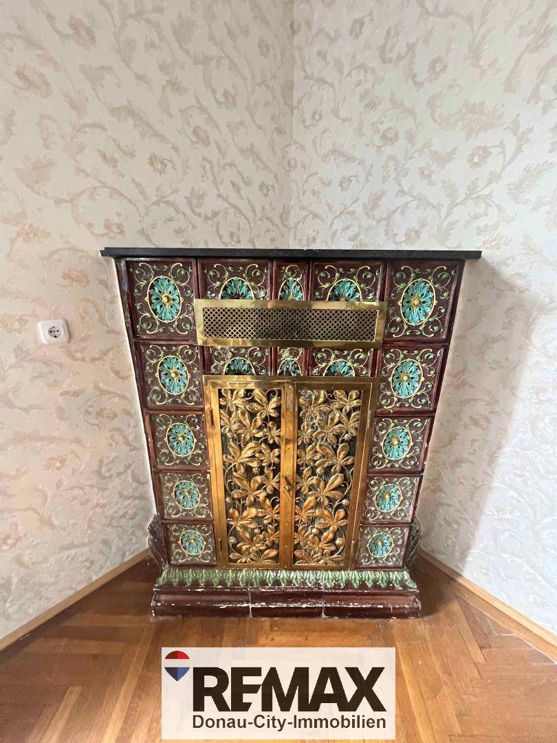 Detailansicht eines kunstvoll verzierten Kachelofens mit floralen Mustern im Wohnzimmer.