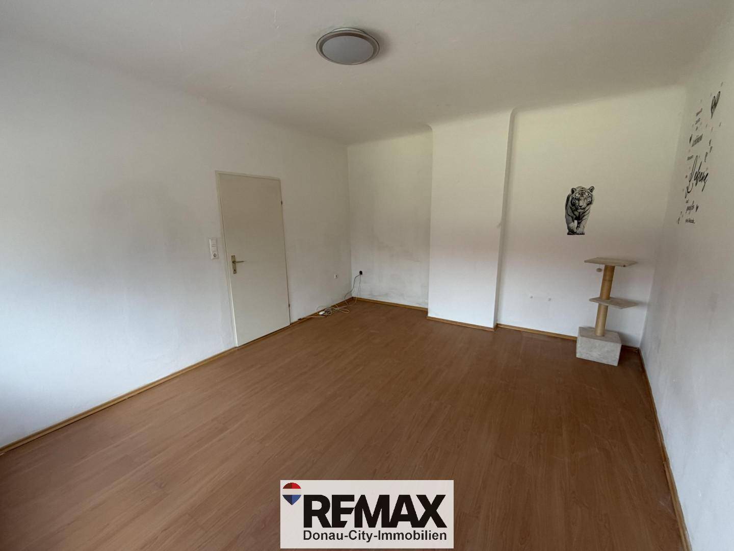 Helles Zimmer mit Laminatboden und schlichten Wänden, bietet Raum für persönliche Einrichtung.