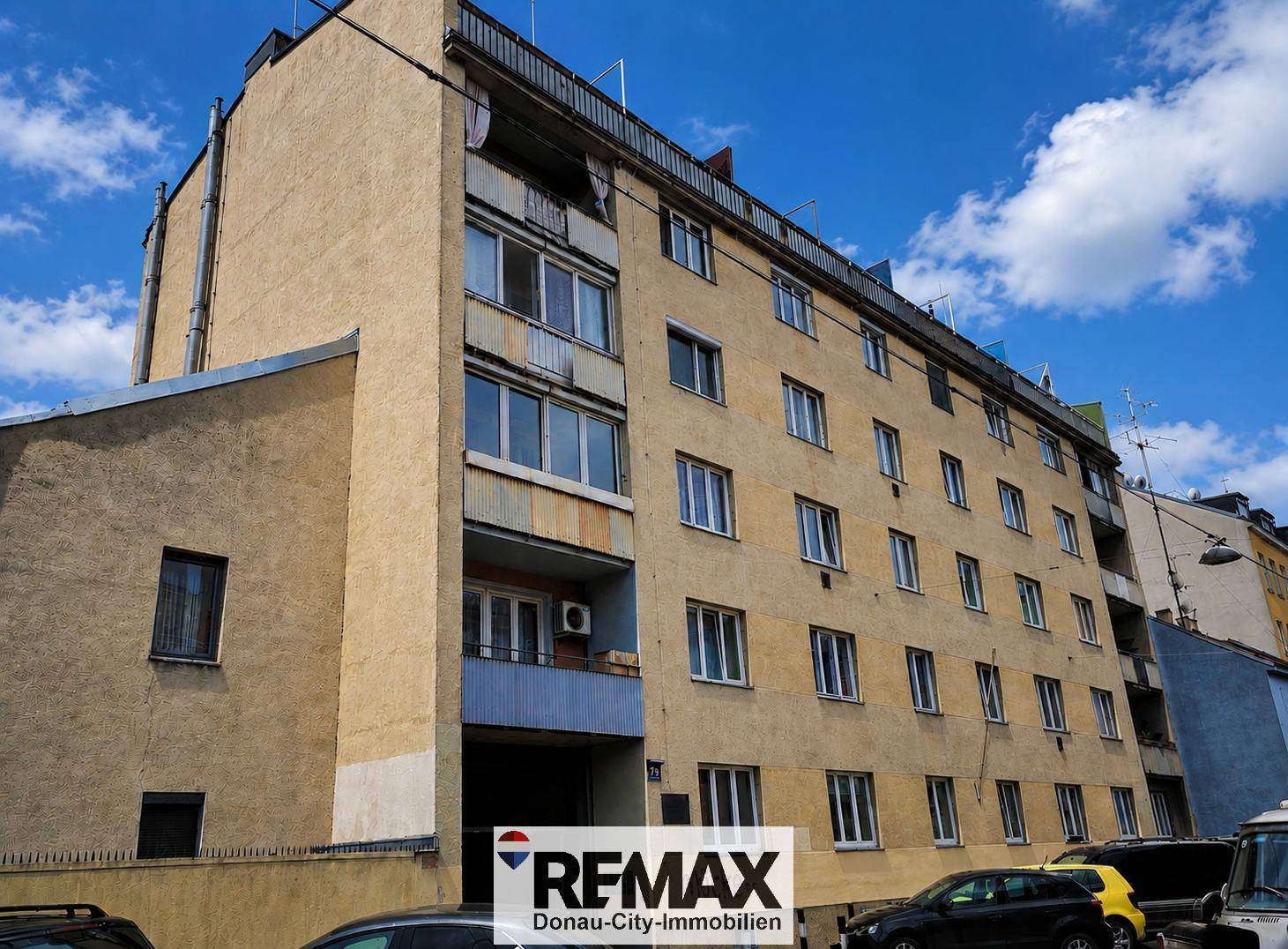 Mehrstöckiges Wohngebäude mit Balkonen und Fenstern unter blauem Himmel, typisch für die Stadt.