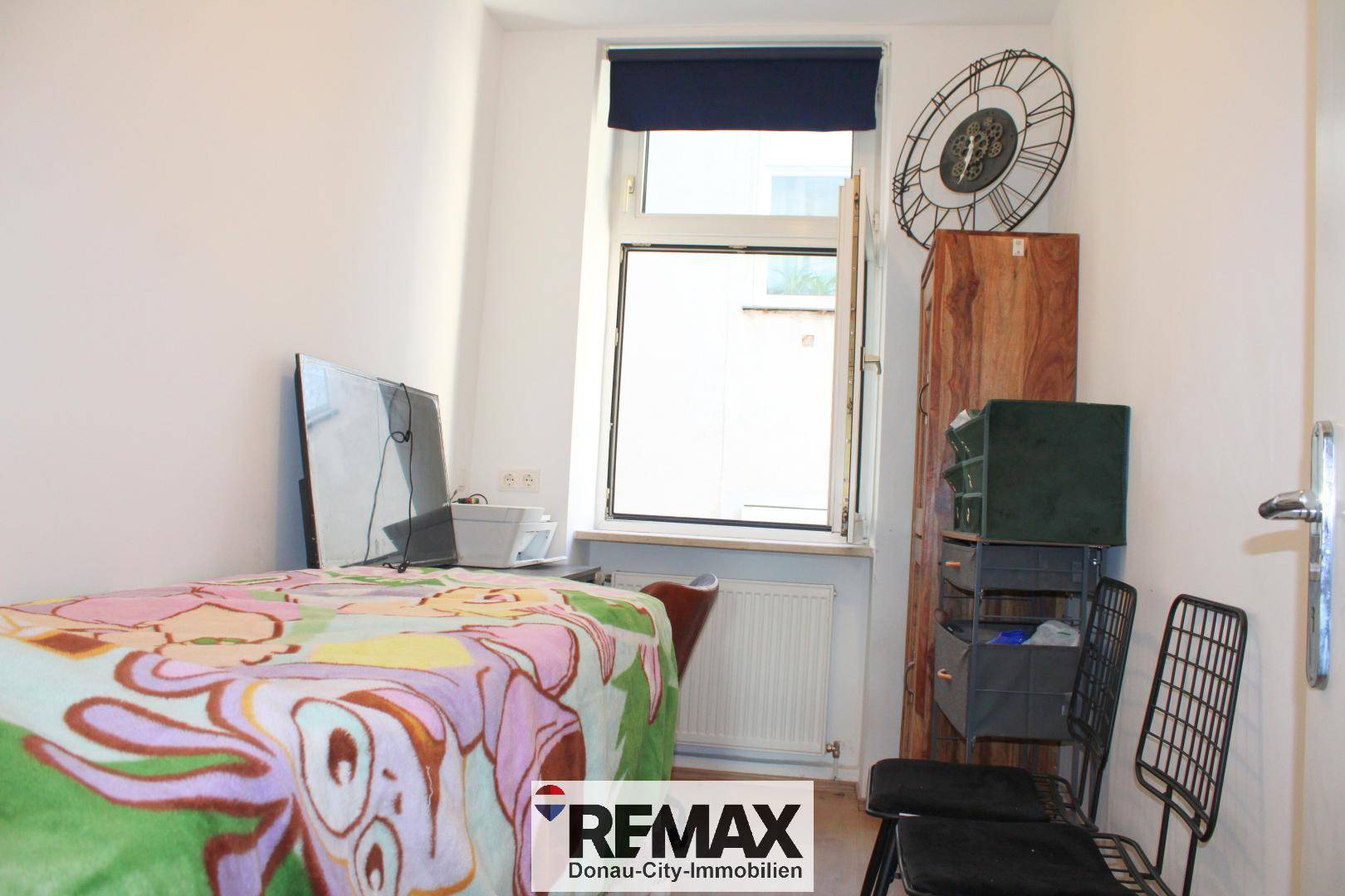 Kleines Schlafzimmer mit Einzelbett, Fernseher und einem Fenster mit Blick nach draußen.