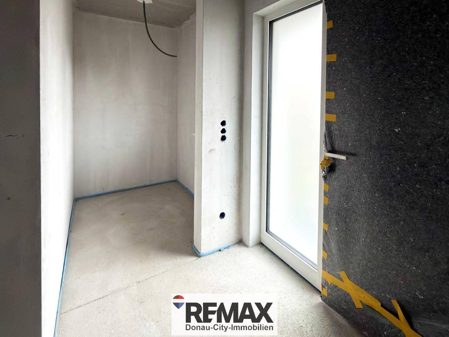 Rohbau-Innenraum mit Betonboden und Türrahmen, bereit für den weiteren Ausbau.