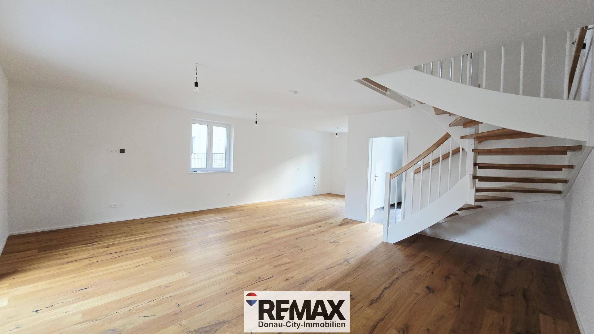 Heller Wohnbereich mit Holzparkett und moderner Wendeltreppe, ideal für offenes Wohnen.