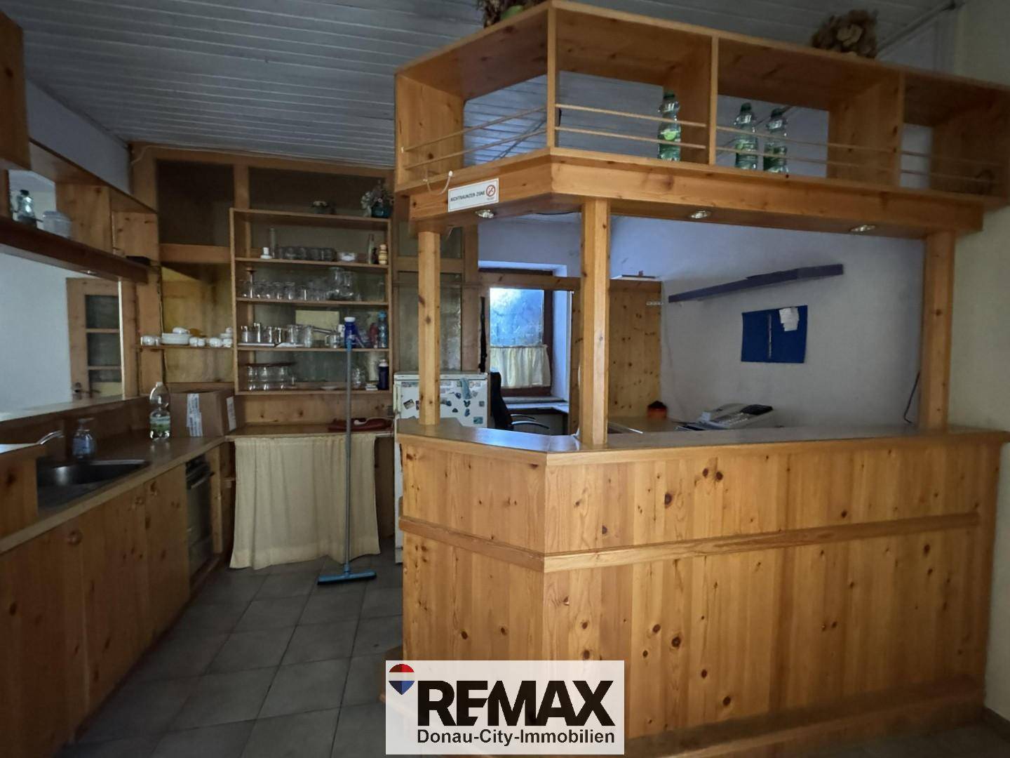 Detailansicht der rustikalen Holzbar mit Spülbecken, Regalen und Gläsern, die eine gemütliche Atmosphäre schafft.
