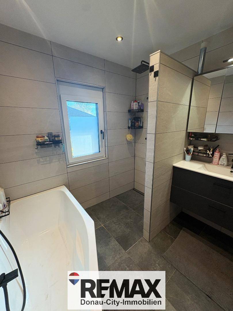 Modernes Badezimmer mit Badewanne, begehbarer Dusche und großformatigen Fliesen.