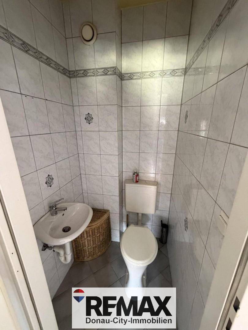 Kleines separates WC mit Fliesen, Toilette und Waschbecken, praktisch und platzsparend.