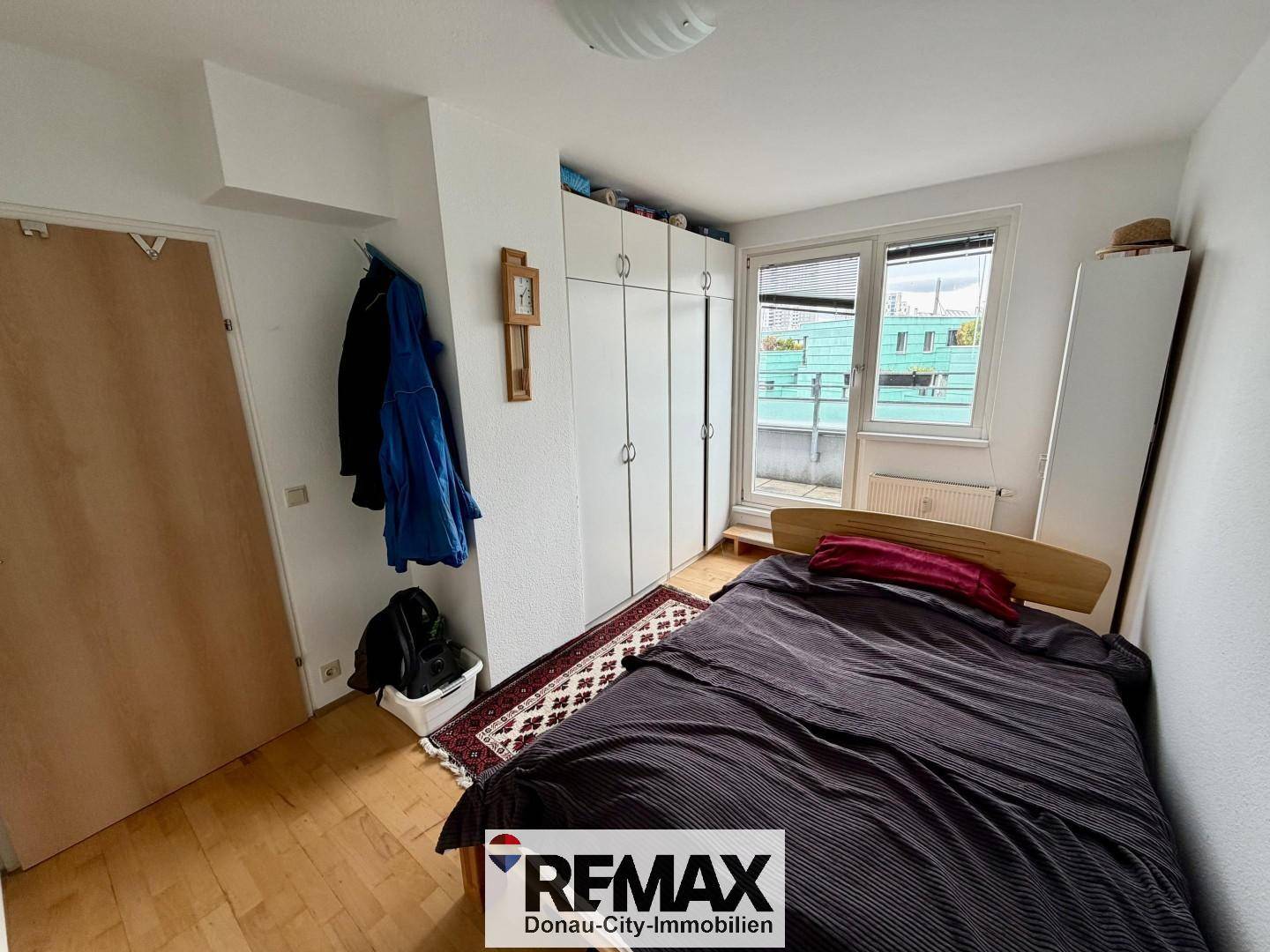 Gemütliches Schlafzimmer mit Holzboden, Kleiderschrank und Fenster mit Jalousien.
