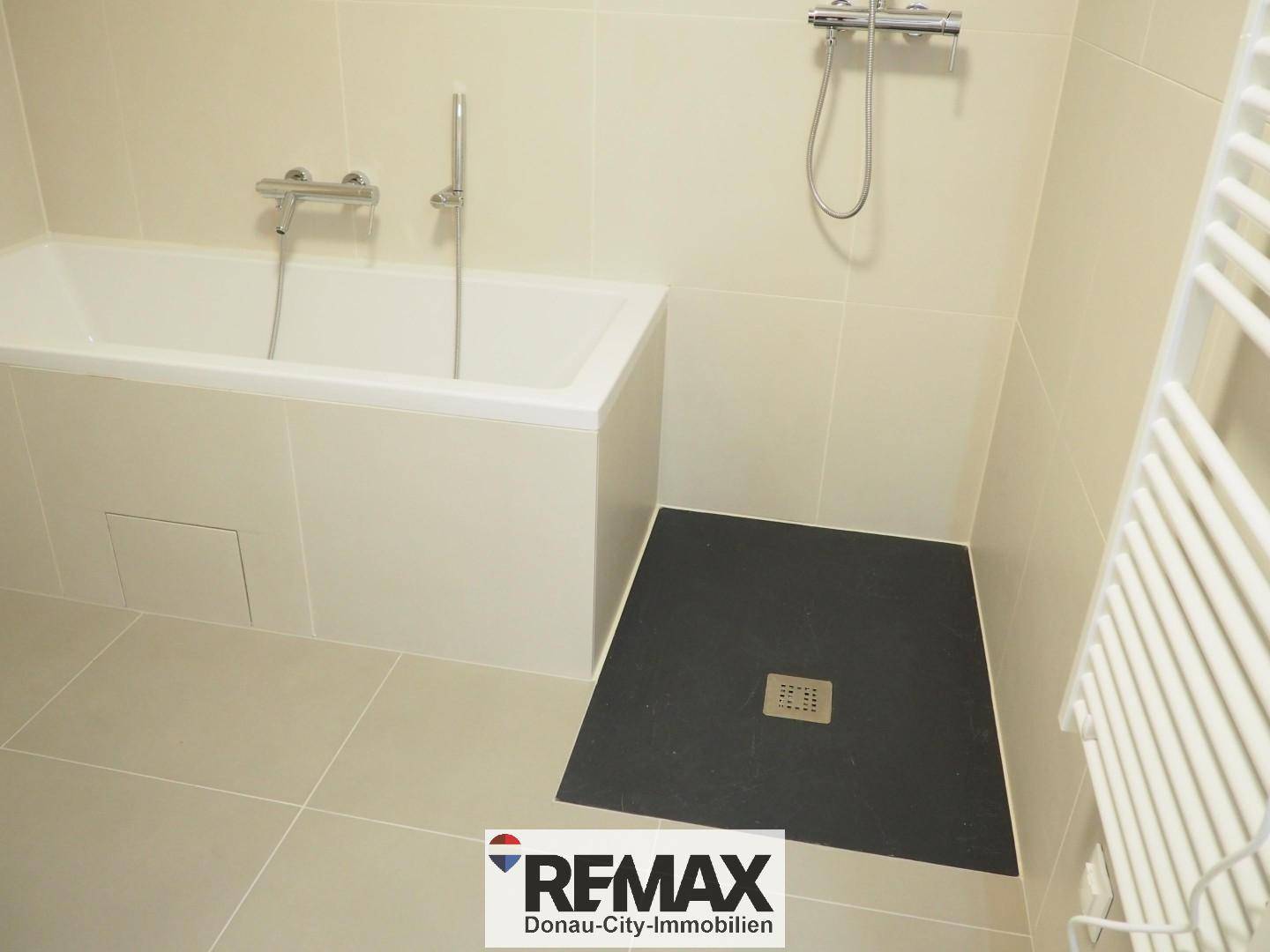 Badezimmer mit Badewanne und ebenerdiger Dusche, in neutralen Farbtönen gehalten.