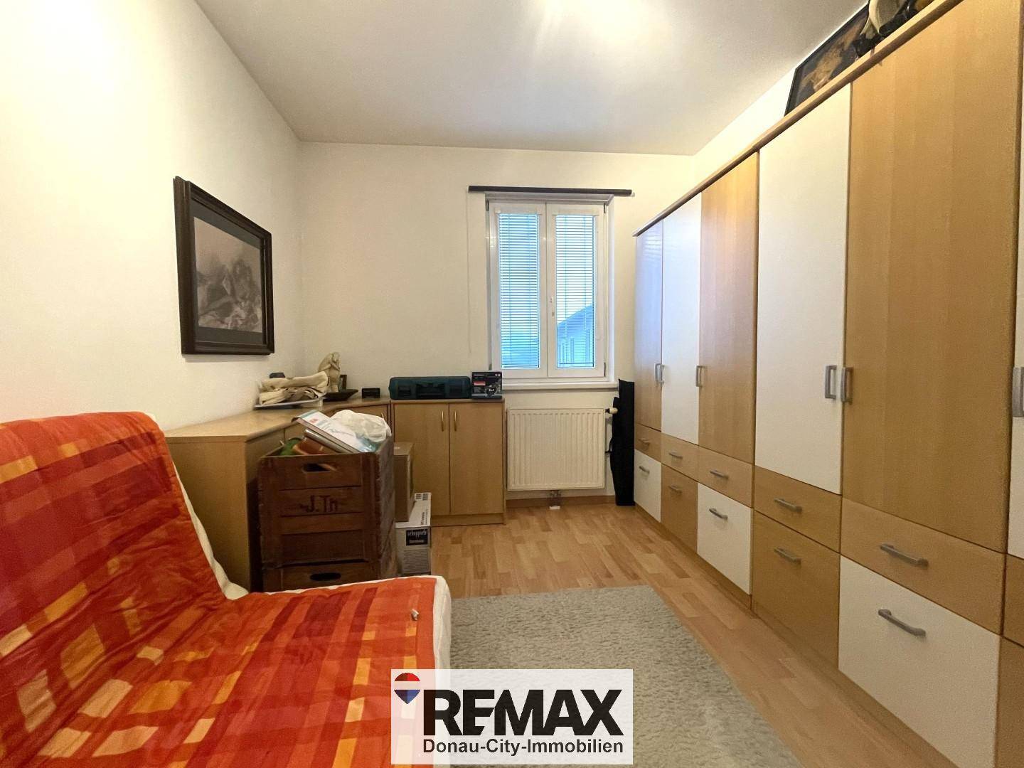 Helles Schlafzimmer mit Laminatboden, großem Kleiderschrank und Fenster.
