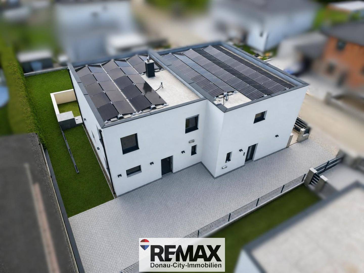 Vorderansicht des modernen Hauses mit gepflasterter Auffahrt und Solarpaneelen auf dem Dach.