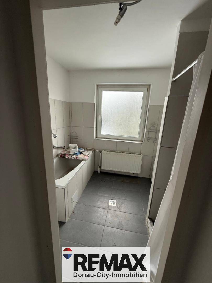 Badezimmer mit Fliesenboden, Badewanne und Fenster, das für Belüftung sorgt.