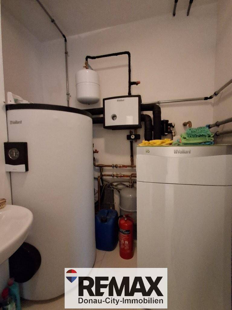 Funktionaler Hauswirtschaftsraum mit Heizungsanlage, Warmwasserspeicher und kleinem Waschbecken.