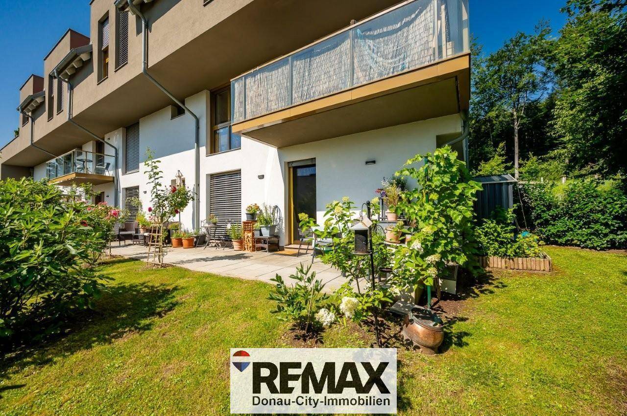 Sonniger Terrassenbereich mit Gartenmöbeln und Zugang zum gepflegten Rasen.