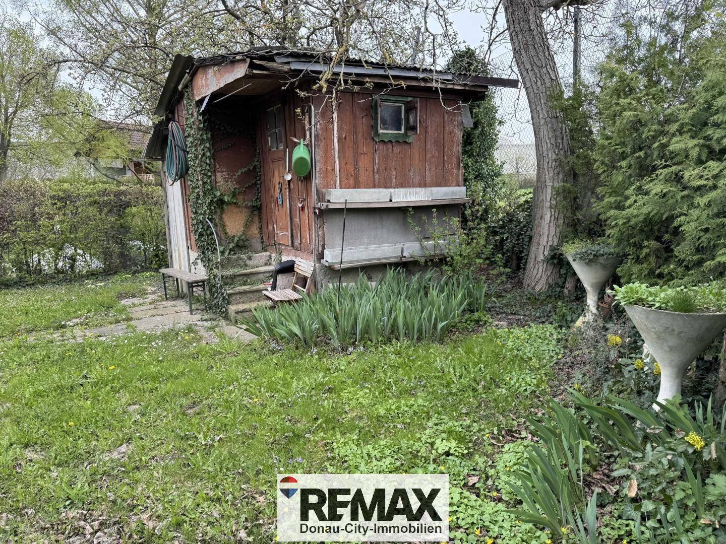 Rustikaler Holzschuppen im Garten, umgeben von Grünflächen und Pflanzen, bietet Stauraum.
