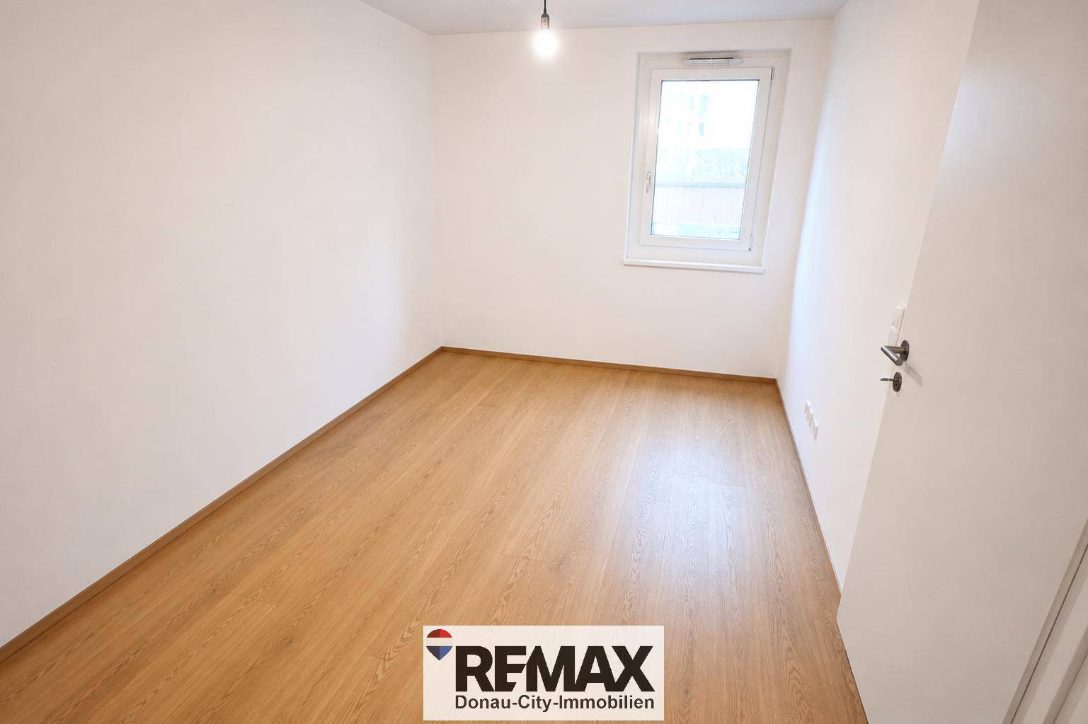 Leeres Zimmer mit Holzboden und einem Fenster, ideal als Schlaf- oder Arbeitszimmer nutzbar.