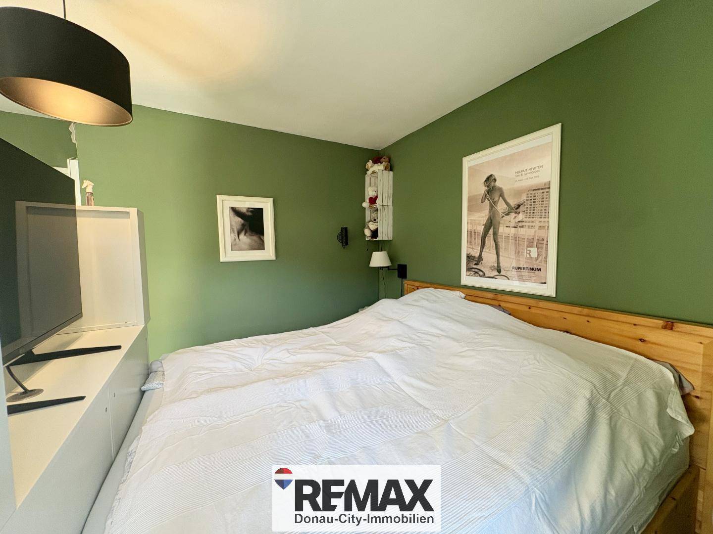 Schlafzimmer mit grün gestrichenen Wänden, Holzbett und schlichter, moderner Einrichtung.