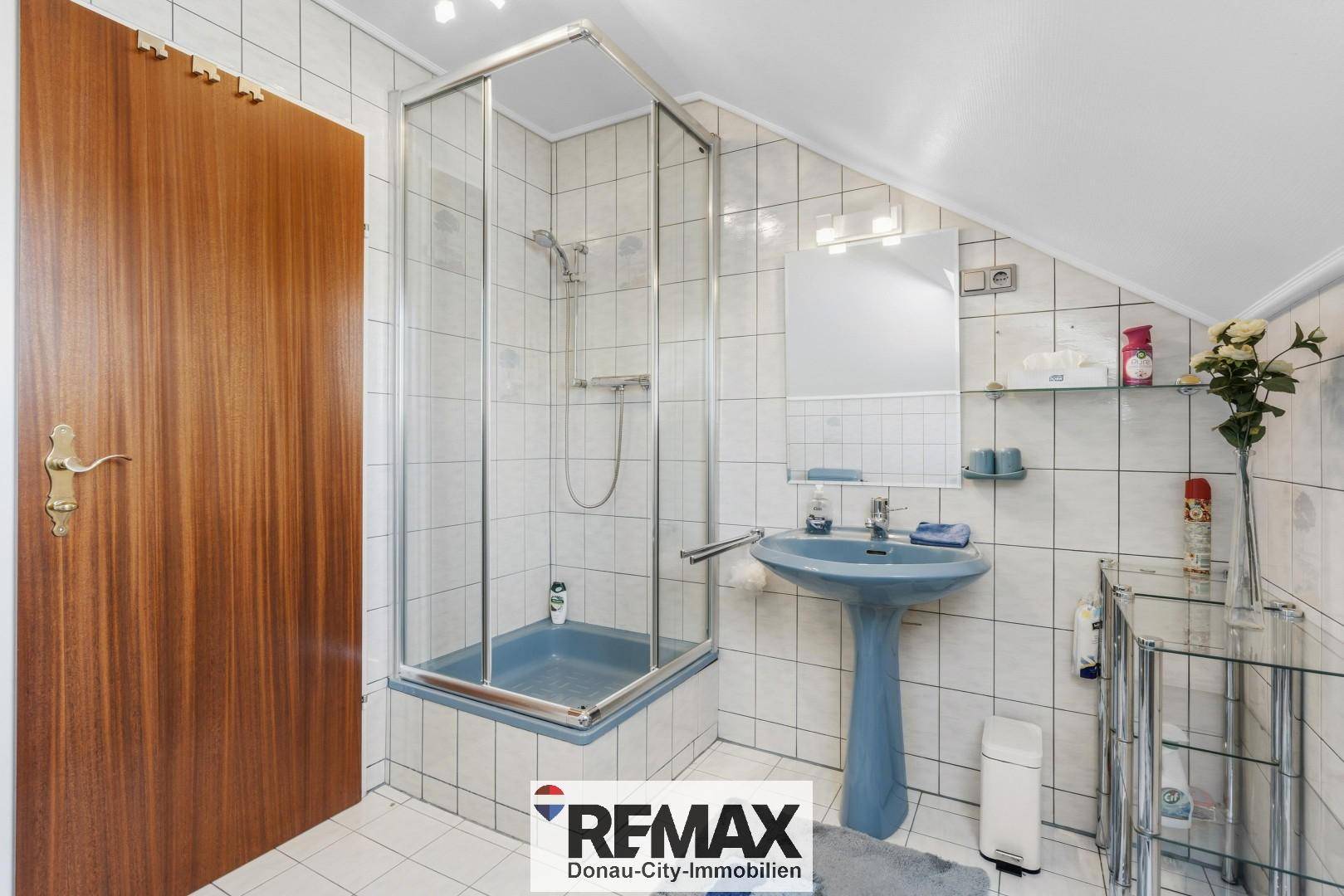 Badezimmer im Dachgeschoss mit Duschkabine, Waschbecken und Fliesen.