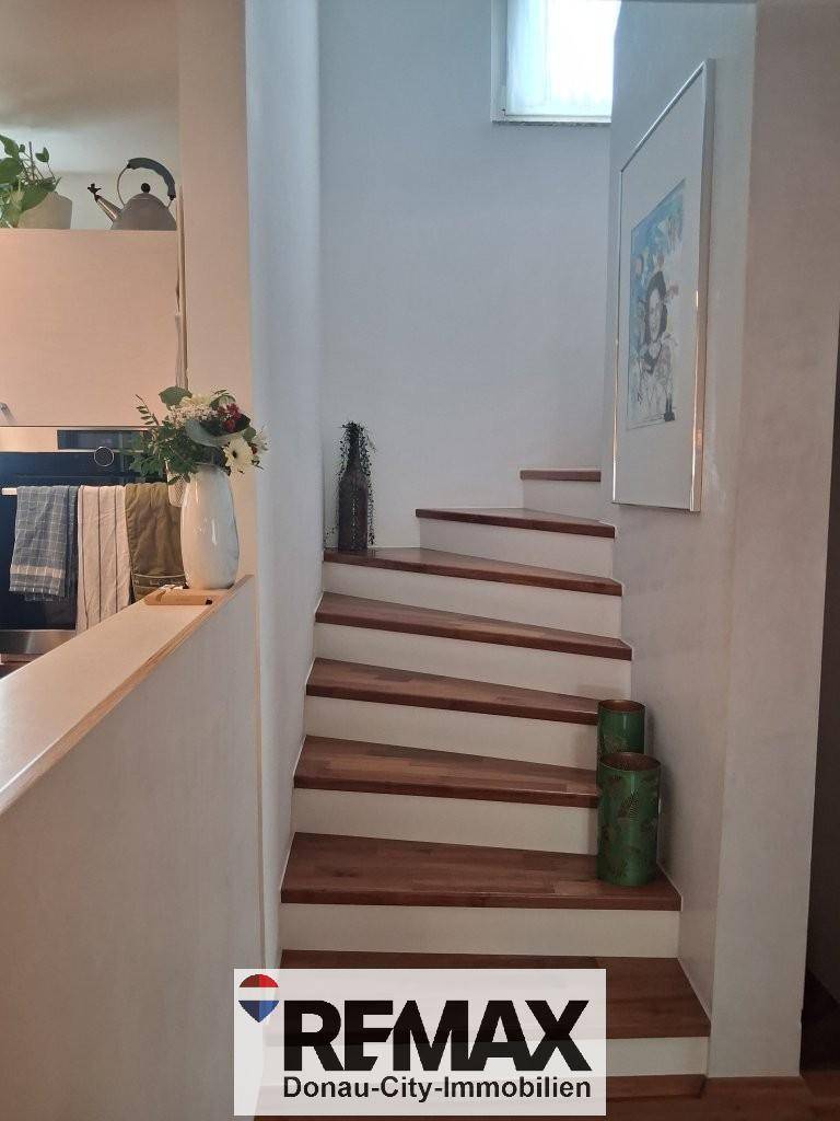 Elegante Holztreppe mit weißen Setzstufen, die in die obere Etage führt.