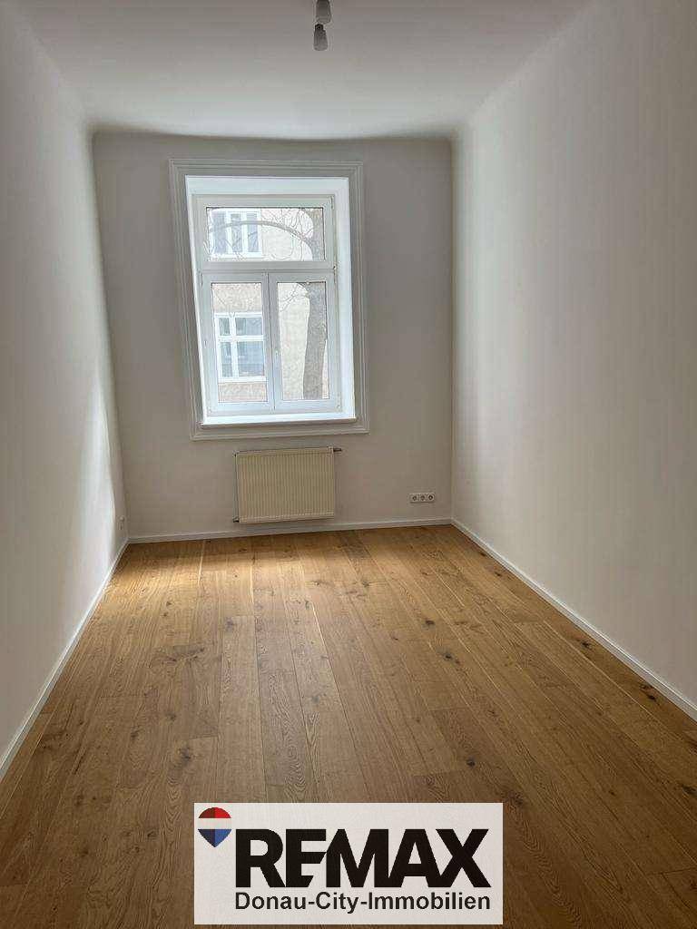 Kleiner, heller Raum mit Holzboden und einem Fenster, ideal als Schlaf- oder Arbeitszimmer.