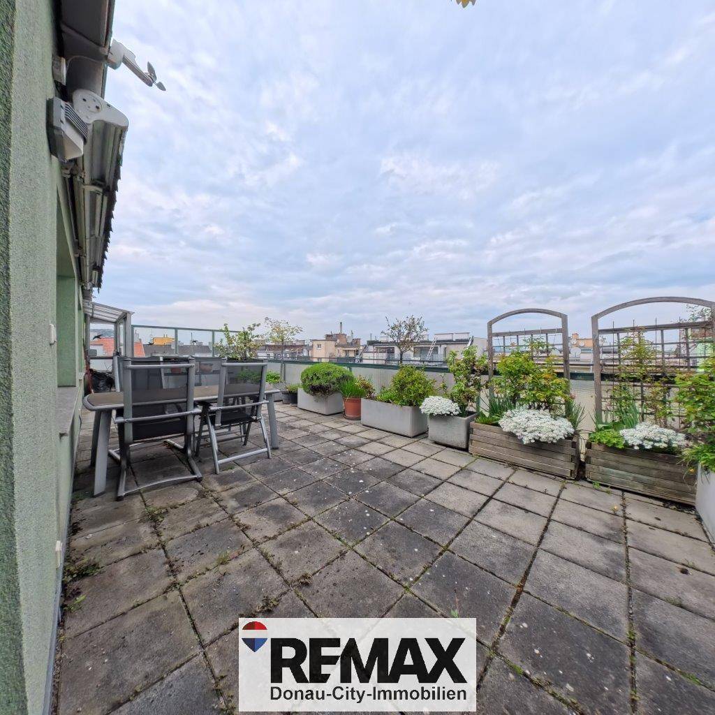Geräumige Dachterrasse mit Steinplatten, Gartenmöbeln und Pflanzen.