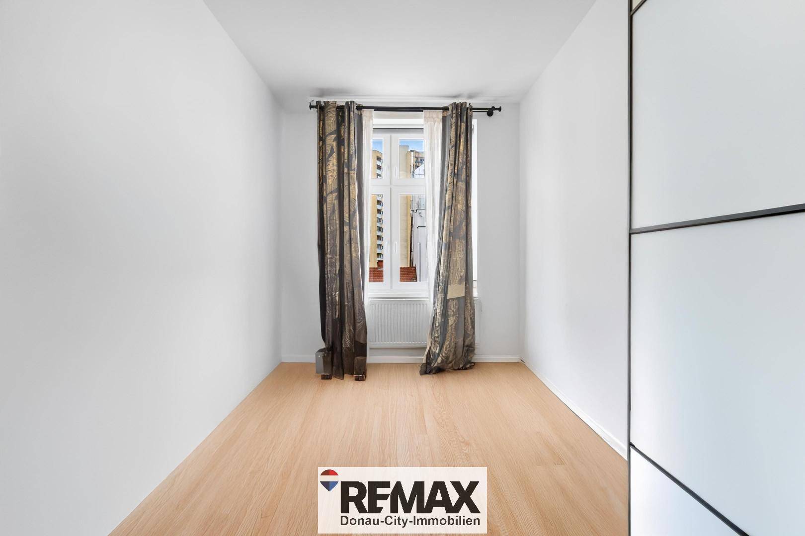 Helles Schlafzimmer mit Holzboden und großem Fenster, bereit zur individuellen Gestaltung.