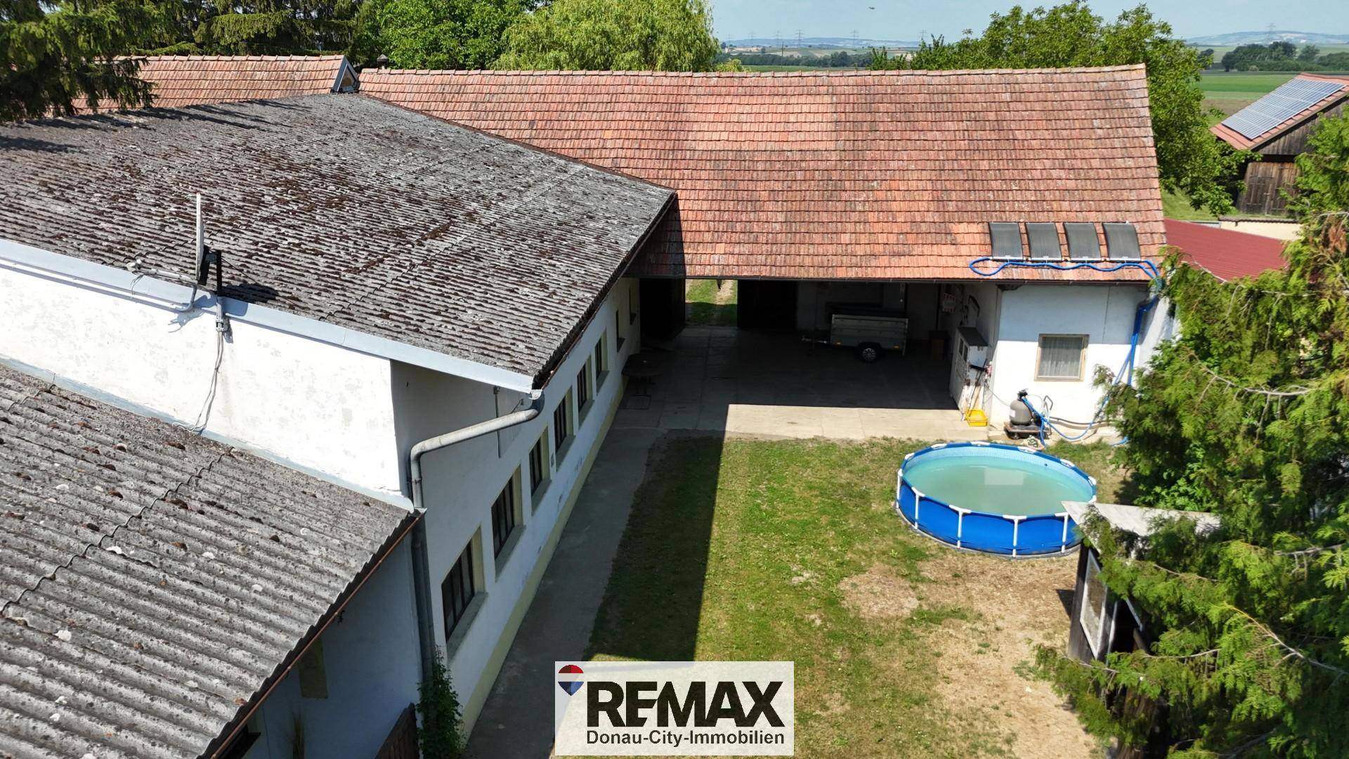 Großer Gartenbereich mit Aufstellpool und angrenzenden Wirtschaftsgebäuden, umgeben von viel Grün.
