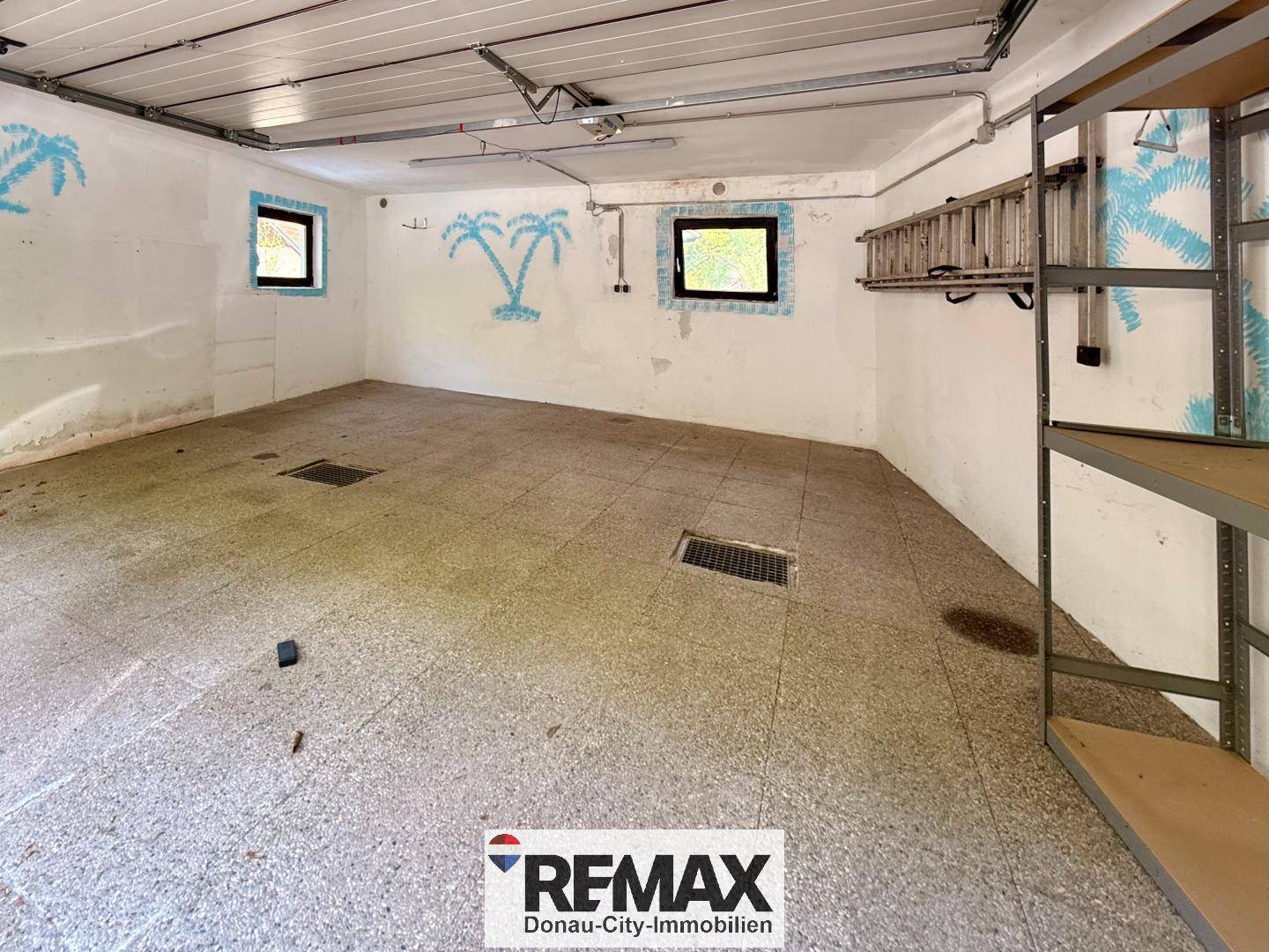 Geräumige Garage oder Abstellraum mit Betonboden und kleinen Fenstern.